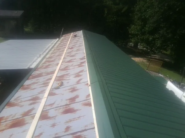 Old rusted panels beside newly installed green metal roofing — Wind Damage Roof Repair by Roofing Brothers in Grove City