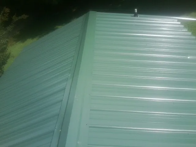 New green metal panels meeting at the ridge of a roof — Flat Roof Repair work by our crew in Grove City