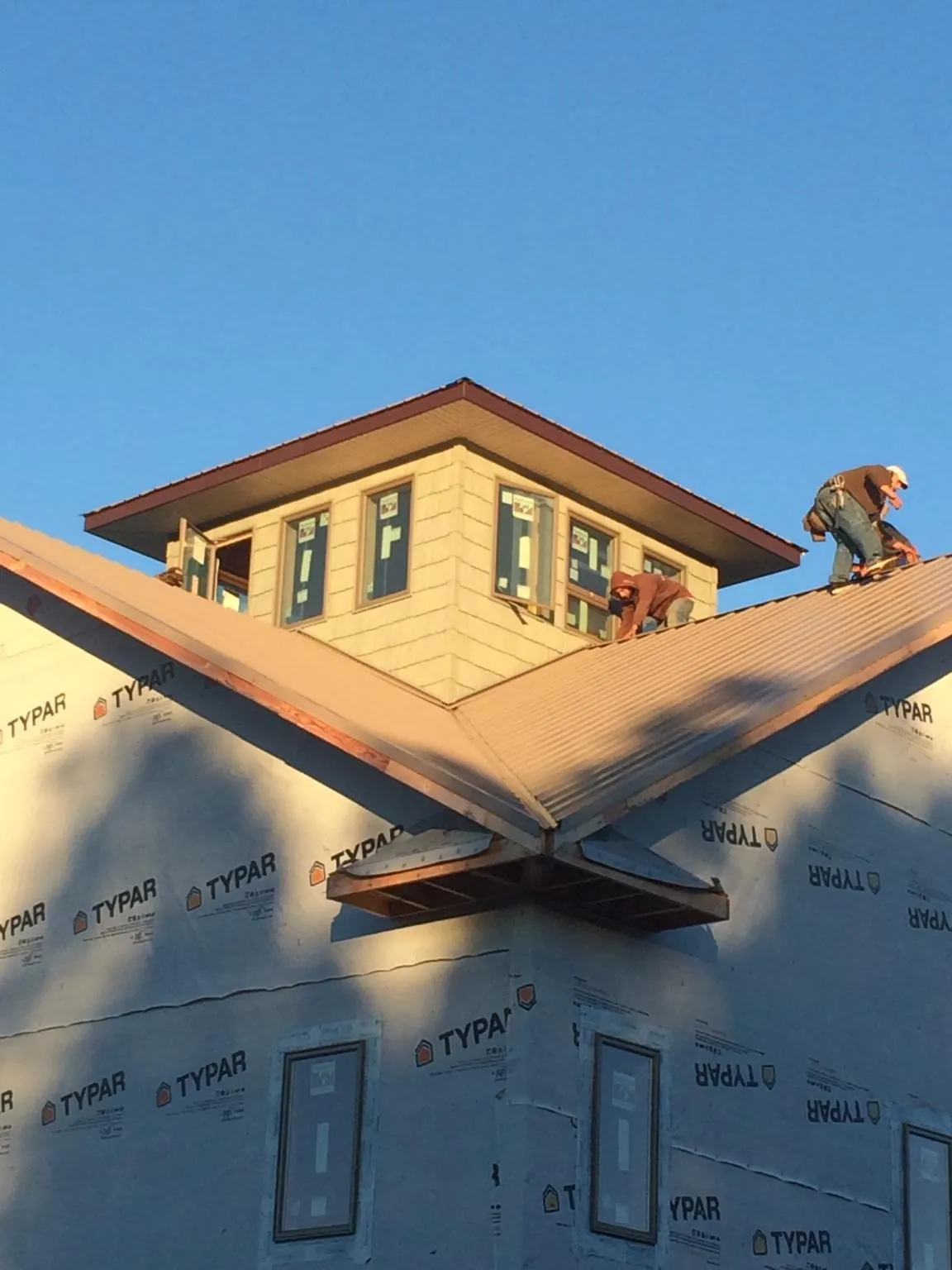 Roofers working around a rooftop cupola on a new metal roof at sunset — Roof Waterproofing in Grove City by Roofing Brothers